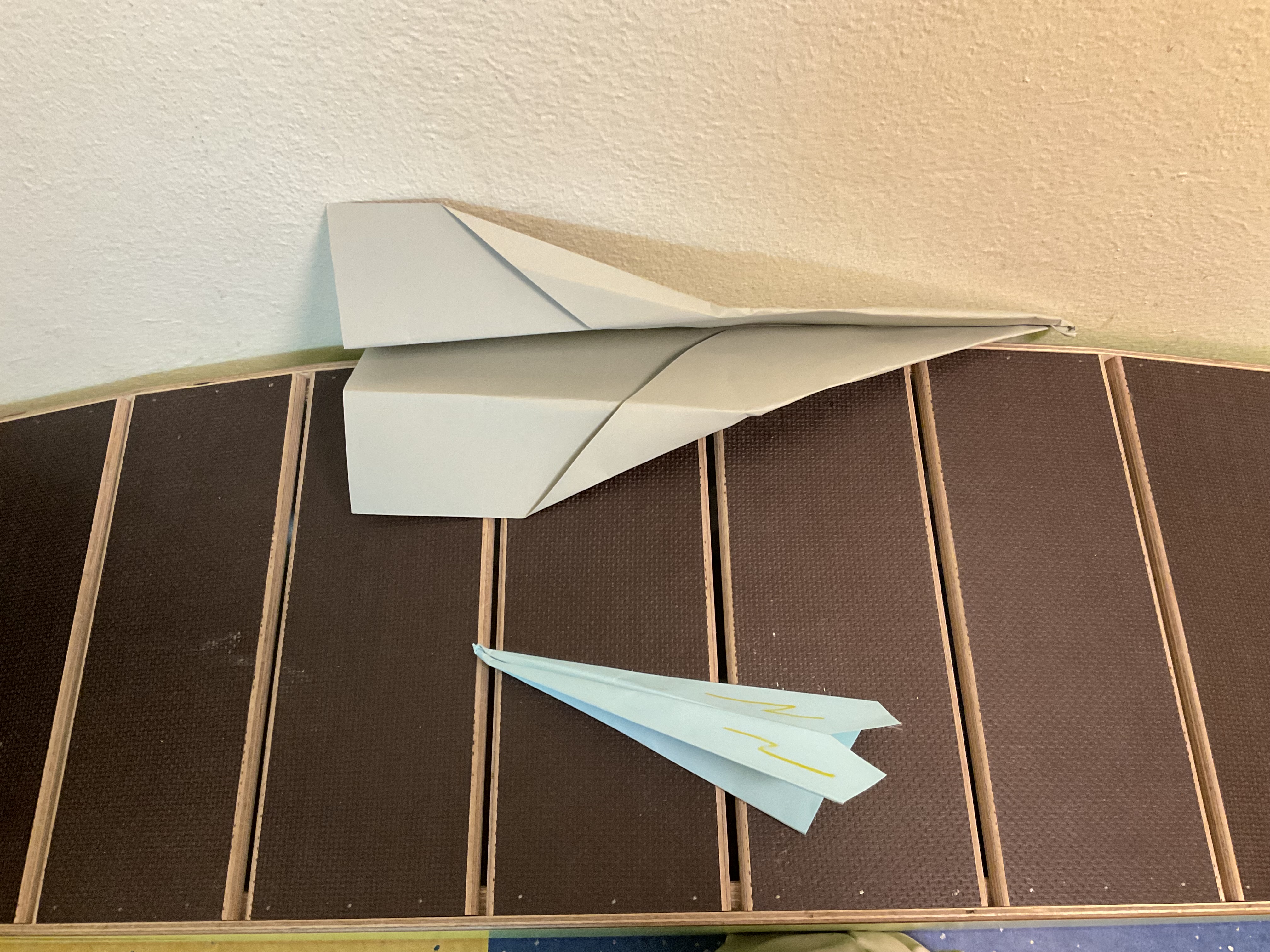Zwei Papierflugzeuge sind auf einer strukturierten Oberfläche zu sehen.